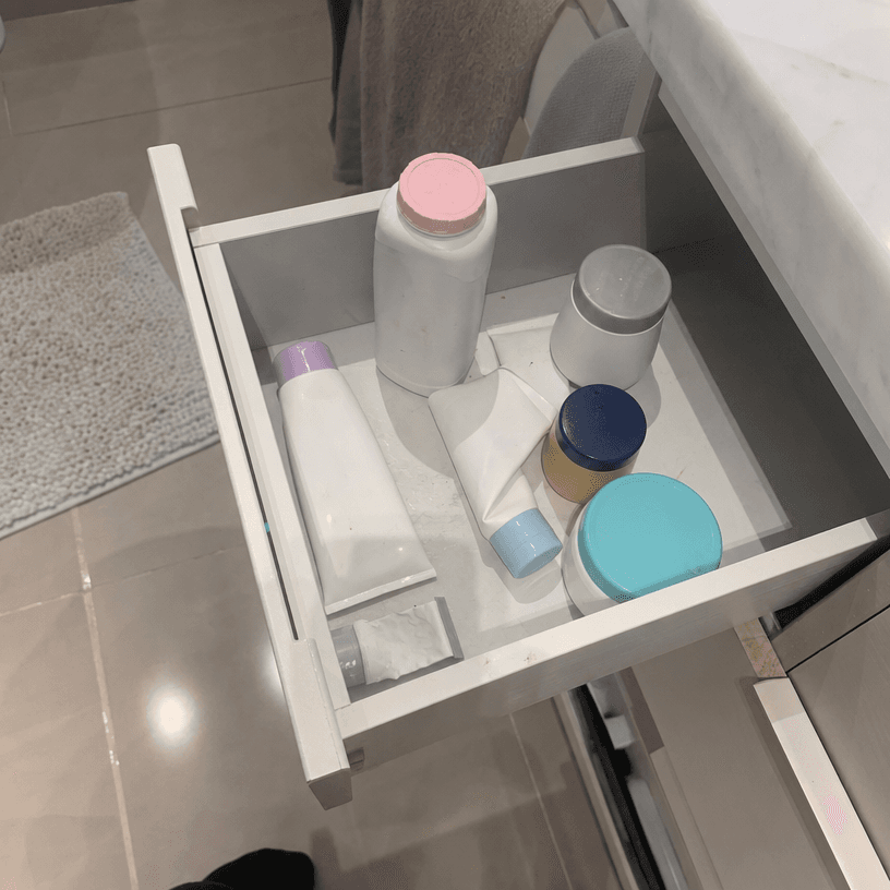 An open bathroom drawer overhead shot showing 6 half-used jars and tubes of generic rash creams jumbled together